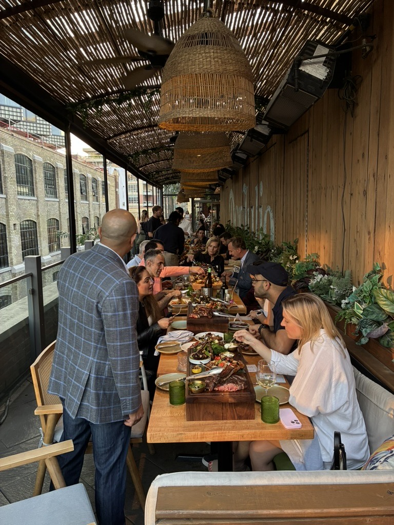 Guests sharing a meal along a long table on a covered terrace